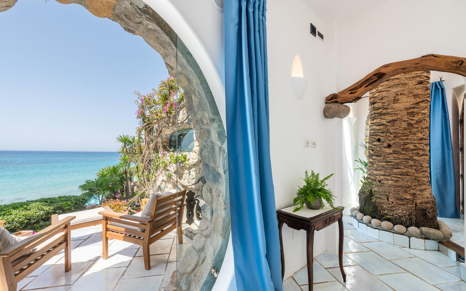 Stone-arch villa room with sea view through blue curtains